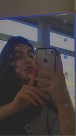 Woman taking selfie with phone, glowing LED frame with heart animations around her face
